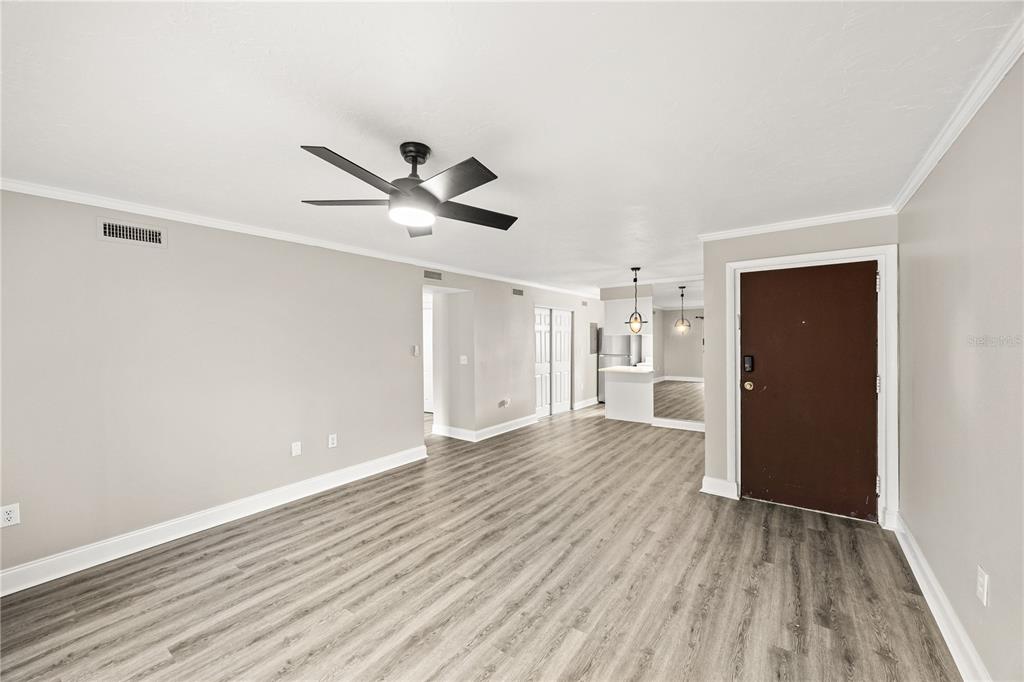 An interior view of a living area with light gray walls, wood-look flooring, and a ceiling fan — 2717 HIDDEN LAKE BOULEVARD UNIT B, SARASOTA, FL