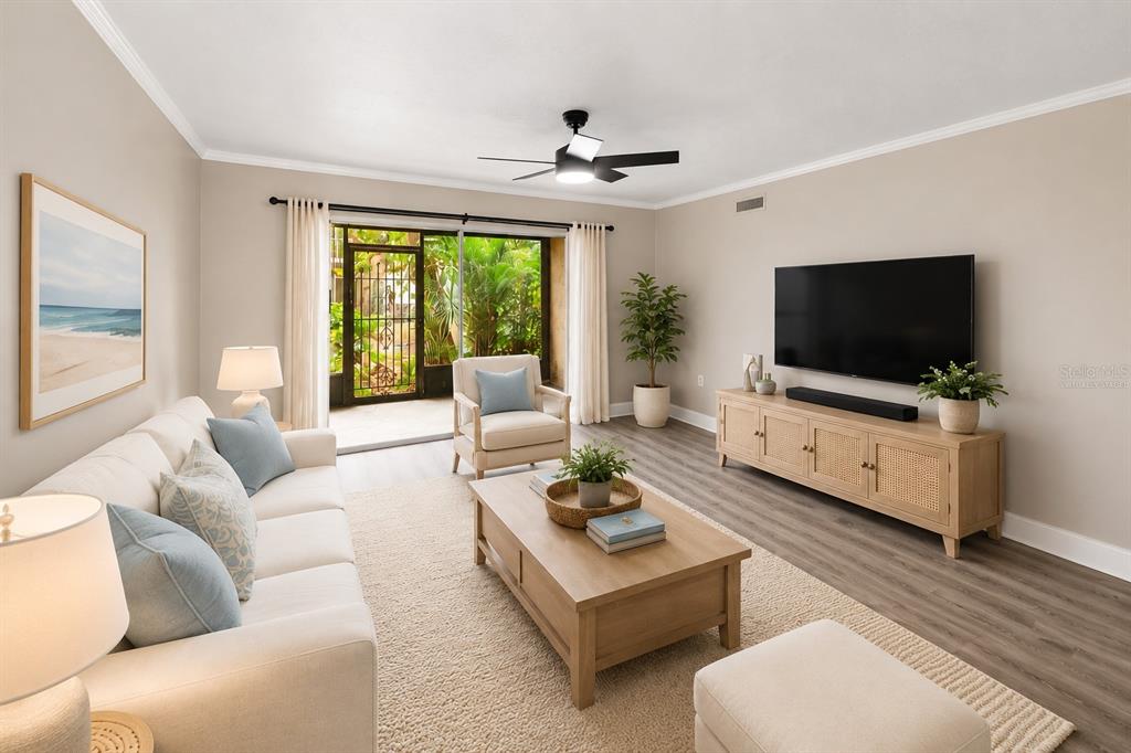 A living room features a beige sofa, wooden coffee table, television, and a sliding glass door — 2717 HIDDEN LAKE BOULEVARD UNIT B, SARASOTA, FL