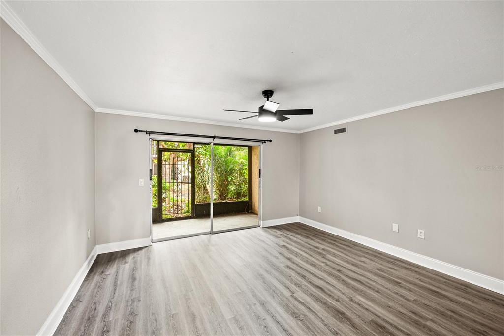 An empty room with gray wood-look flooring, a ceiling fan, and sliding glass patio doors — 2717 HIDDEN LAKE BOULEVARD UNIT B, SARASOTA, FL
