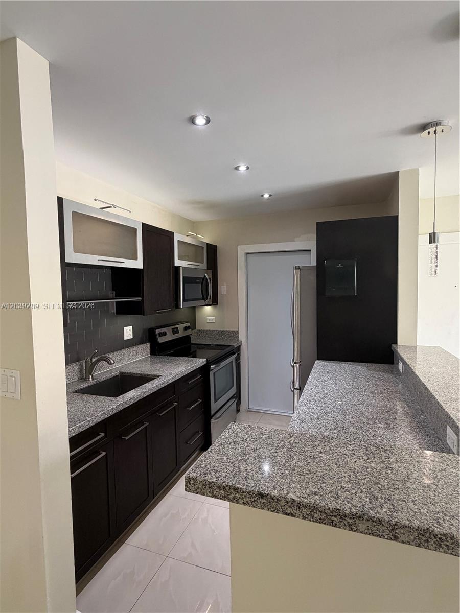 A kitchen features dark cabinetry, granite countertops, a stainless steel sink, and tile flooring — 13872 SW 90th Ave, Miami FL 33176, MIAMI, FL