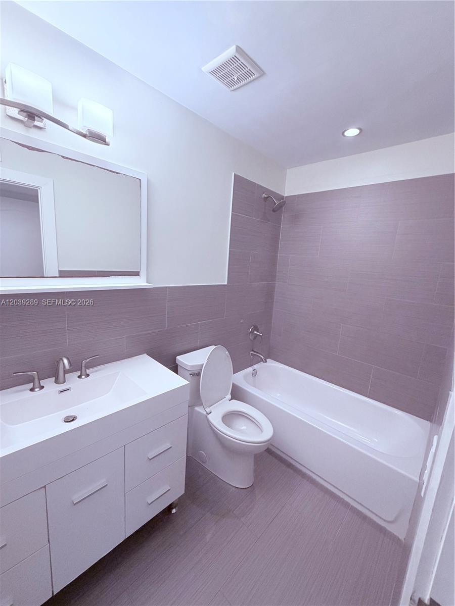 A modern bathroom features a white vanity, a toilet, and a tiled bathtub shower — 13872 SW 90th Ave, Miami FL 33176, MIAMI, FL