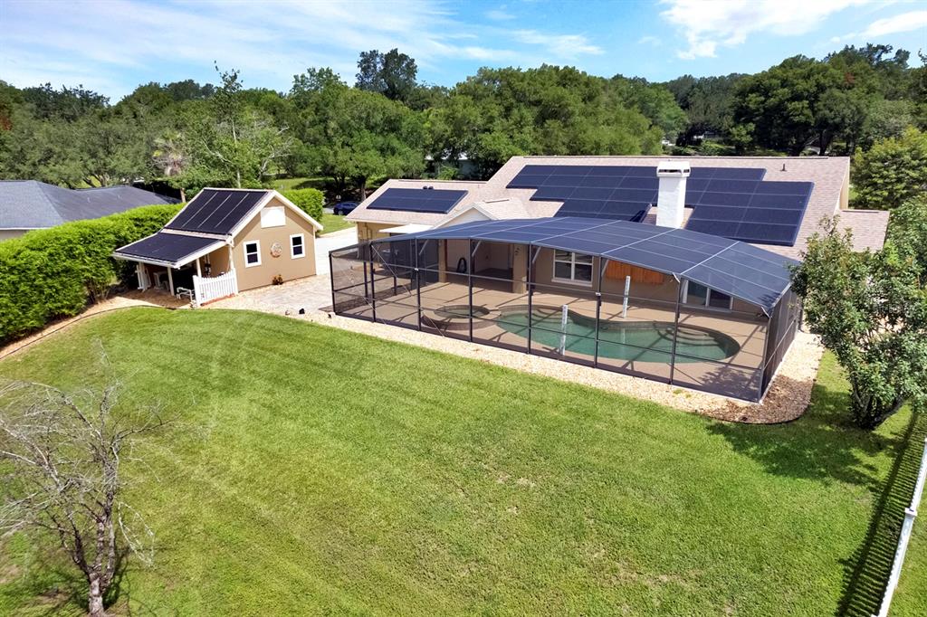 An aerial view shows a house with solar panels, a screened pool, and a detached garage — 10502 LAKE HILL DRIVE, CLERMONT, FL