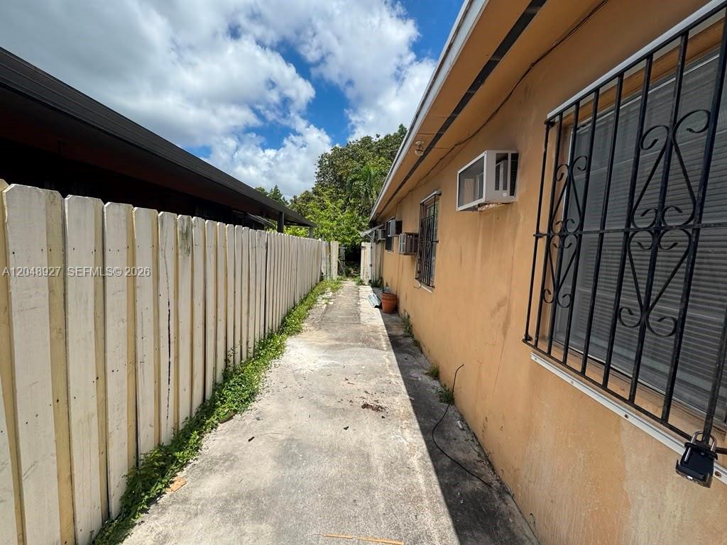A concrete walkway runs between a wooden fence and the side of a house — 1236 NW 33rd Ave # 1, Miami FL 33125, MIAMI, FL