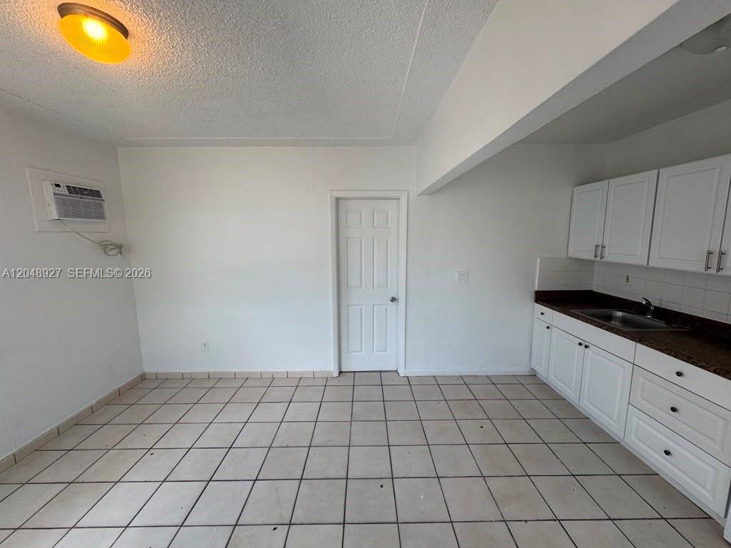 A kitchen area features white cabinets, a dark countertop, and light-colored floor tiles — 1236 NW 33rd Ave # 1, Miami FL 33125, MIAMI, FL