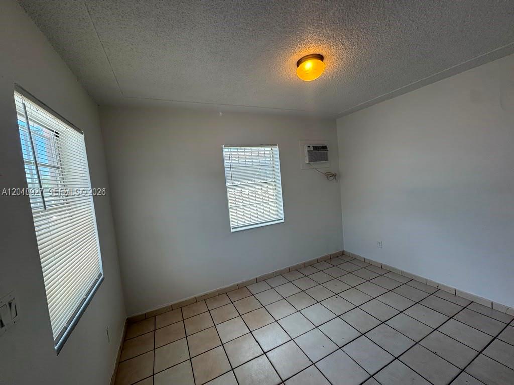 An empty room features white walls, a tiled floor, two windows, and a ceiling light — 1236 NW 33rd Ave # 1, Miami FL 33125, MIAMI, FL