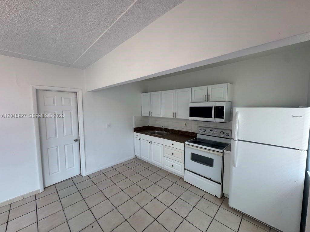 A kitchen features white cabinets, a white stove, a microwave, and a white refrigerator — 1236 NW 33rd Ave # 1, Miami FL 33125, MIAMI, FL