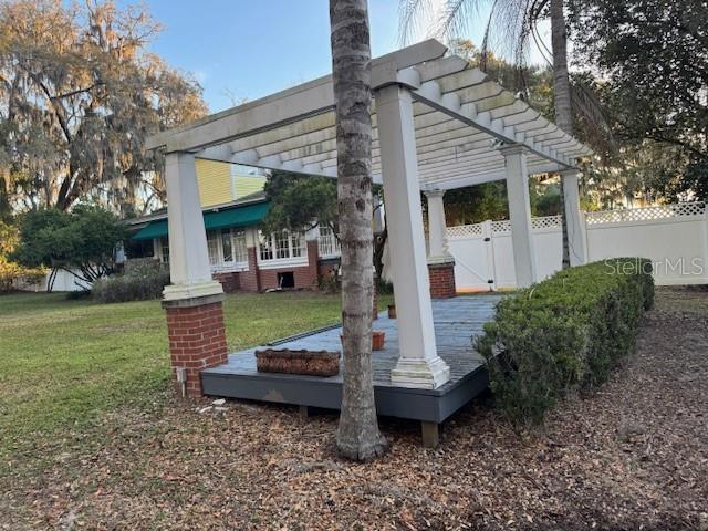 A wooden pergola with white columns stands on a deck in a grassy yard — 11294 N US HIGHWAY 301, OXFORD, FL