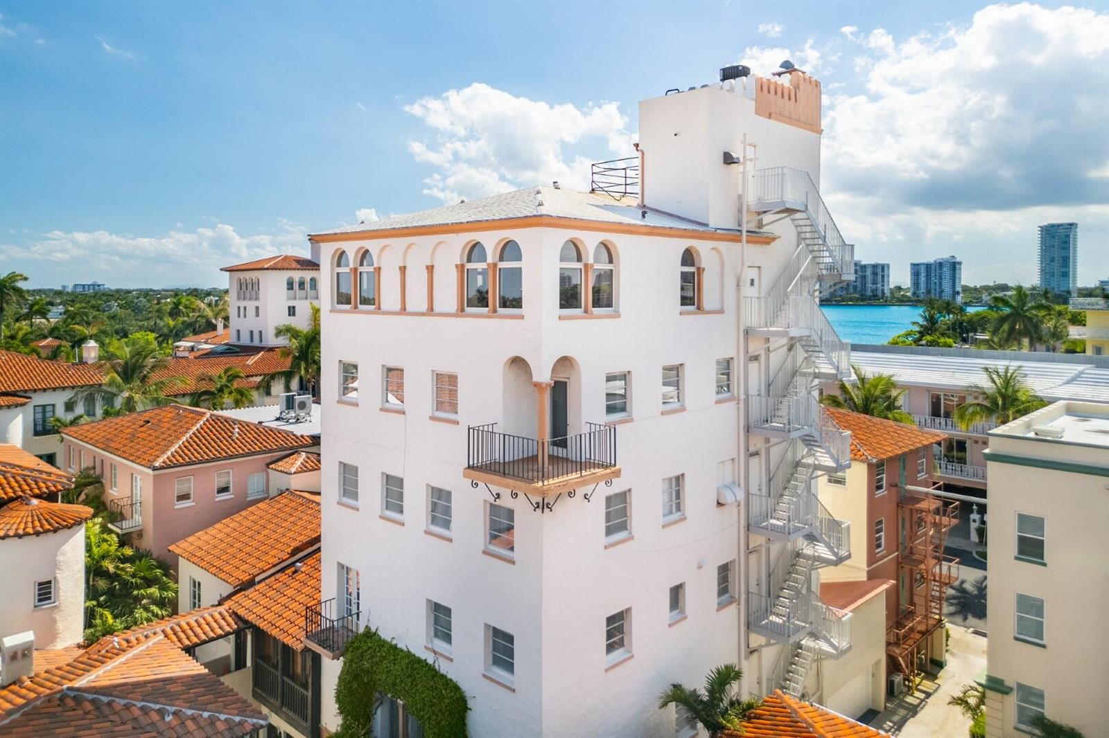 An exterior view of a multi-story white building with a metal fire escape and balcony — 9 Via Parigi, Palm Beach FL 33480, PALM BEACH, FL