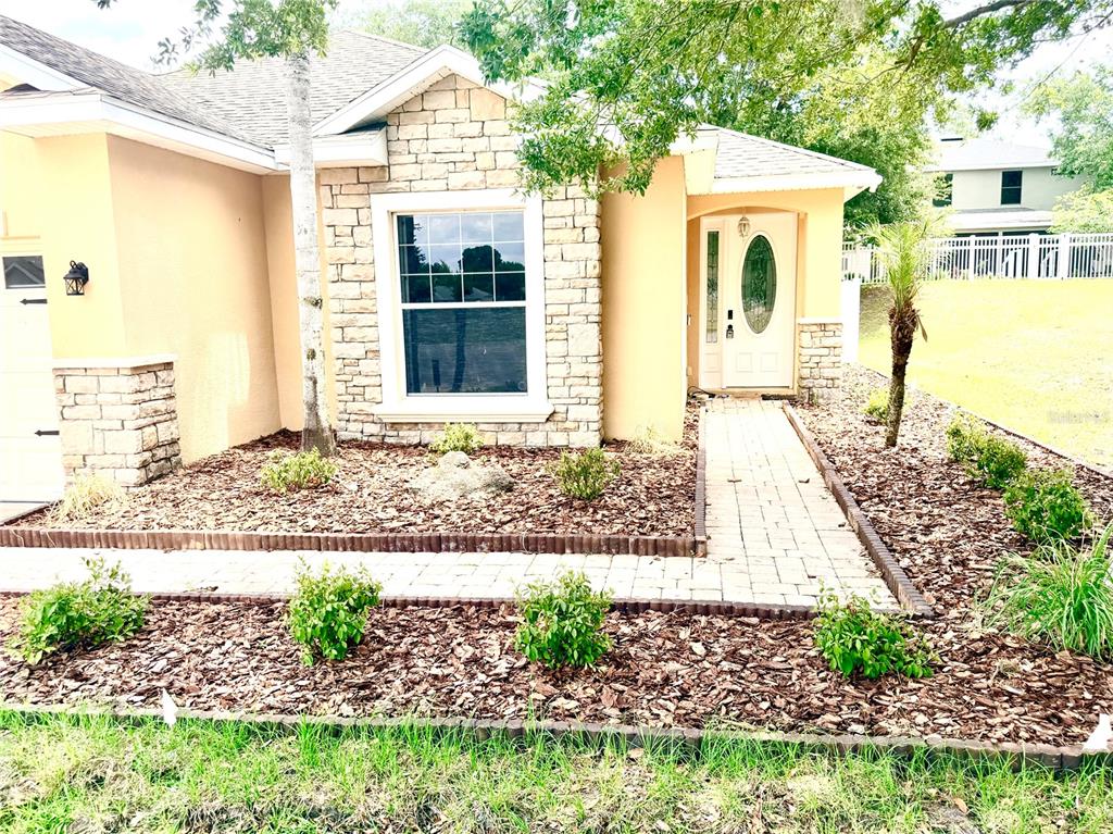 A single-story house with stone accents, a paved walkway, and a landscaped front yard — 1541 HACKNEY TERRACE, DELAND, FL