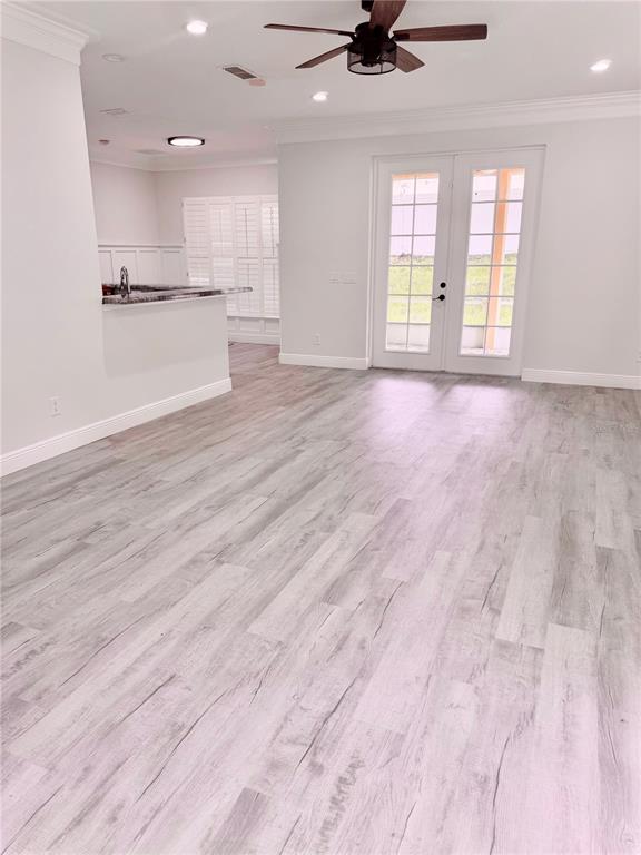 A bright living area with light wood-look flooring, a ceiling fan, and glass patio doors — 1541 HACKNEY TERRACE, DELAND, FL