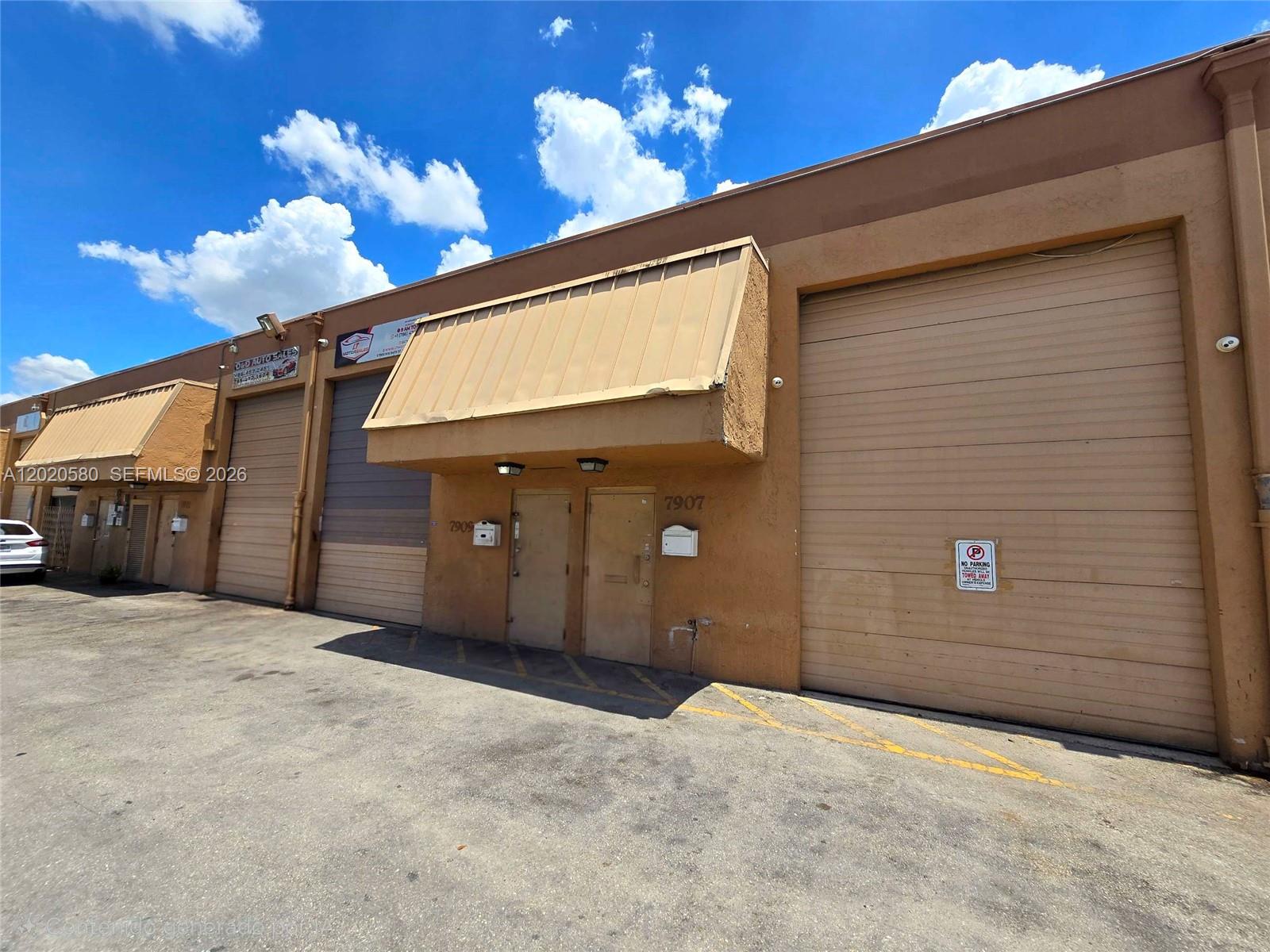 An exterior view of a commercial warehouse building with two roll-up doors and two entrance doors — 7909 NW 64th St # 7909, Medley FL 33166, MEDLEY, FL
