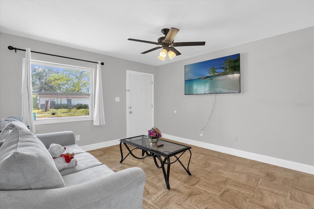 A living room features light gray walls, tile flooring, a sofa, and a wall-mounted television — 5390 BOTANY COURT, ORLANDO, FL