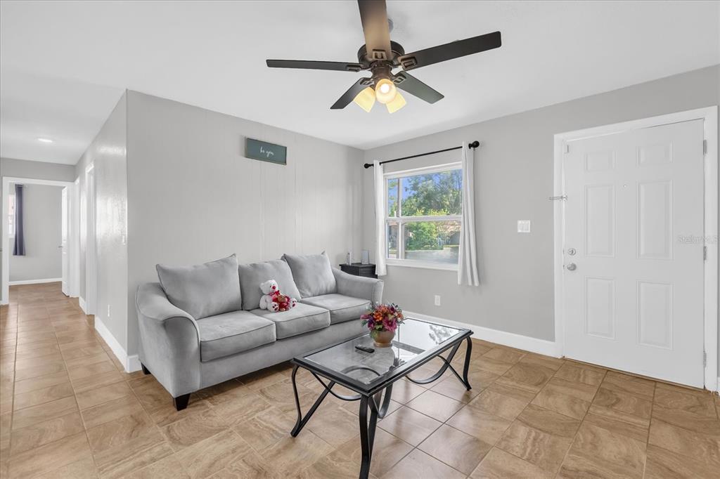 A living room features light gray walls, tile flooring, a gray sofa, and a ceiling fan — 5390 BOTANY COURT, ORLANDO, FL