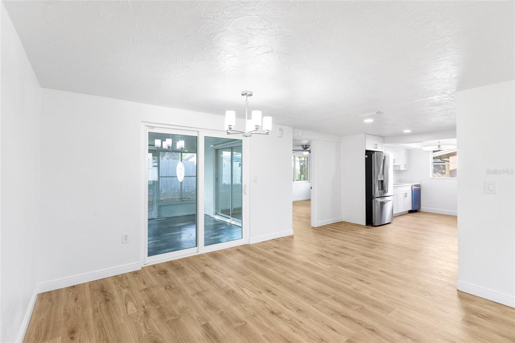A dining area with wood-look flooring, a chandelier, and sliding glass doors to a patio — 6239 7TH AVENUE, NEW PORT RICHEY, FL