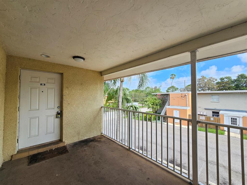 An exterior balcony with a white door, metal railing, and a view of a parking lot — 117 N EVERGREEN AVENUE UNIT 205, CLEARWATER, FL