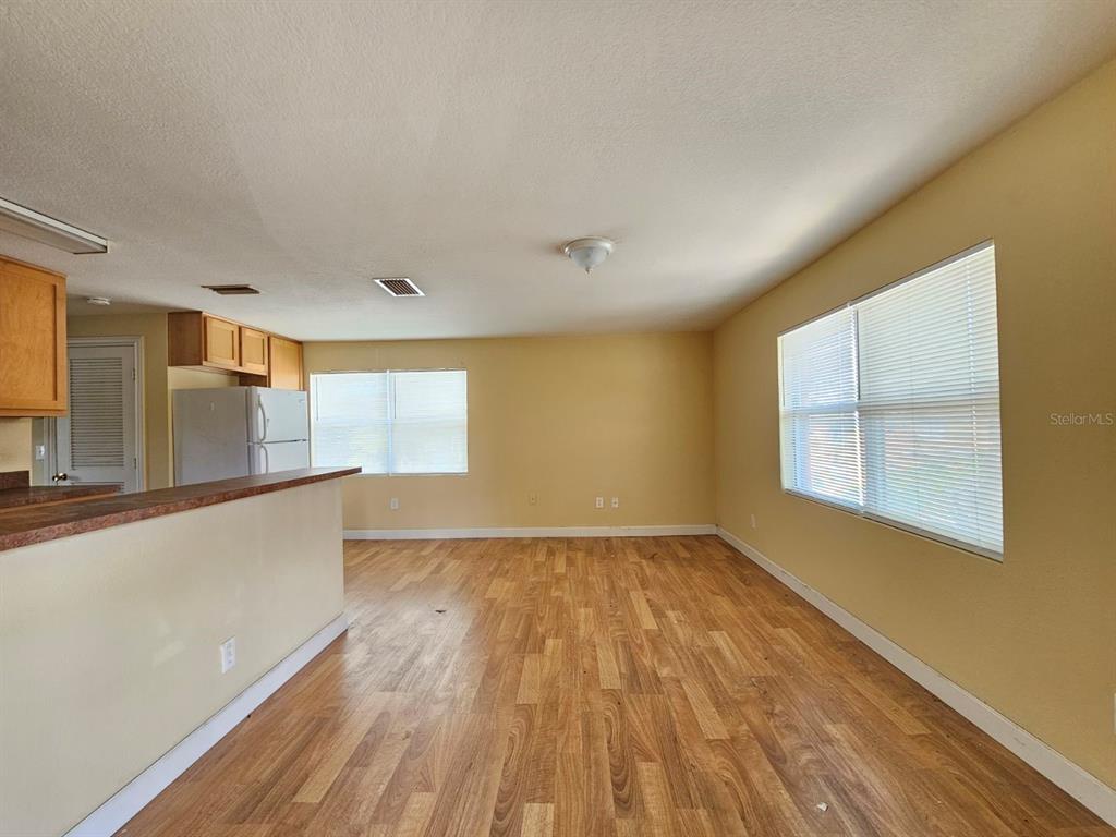 An open-concept living area features wood-look flooring, yellow walls, and a kitchen with wooden cabinets — 117 N EVERGREEN AVENUE UNIT 205, CLEARWATER, FL