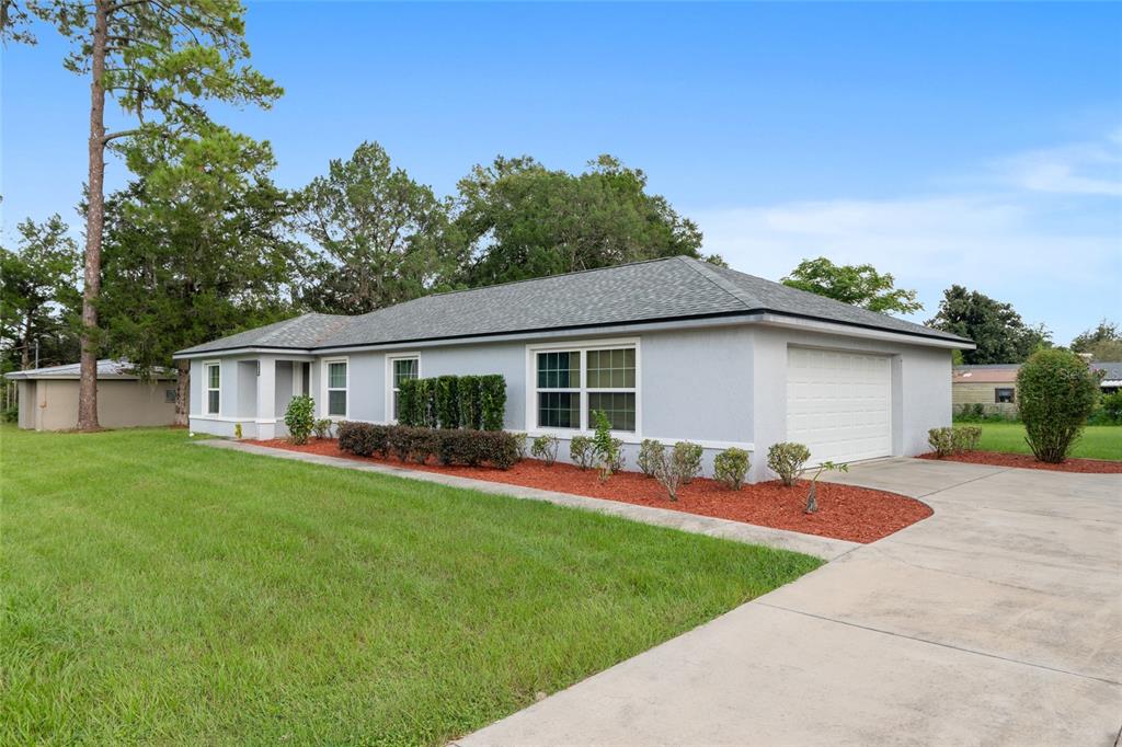A light gray single-story house with a white garage door and red mulch landscaping — 3424 NE 14TH STREET, OCALA, FL