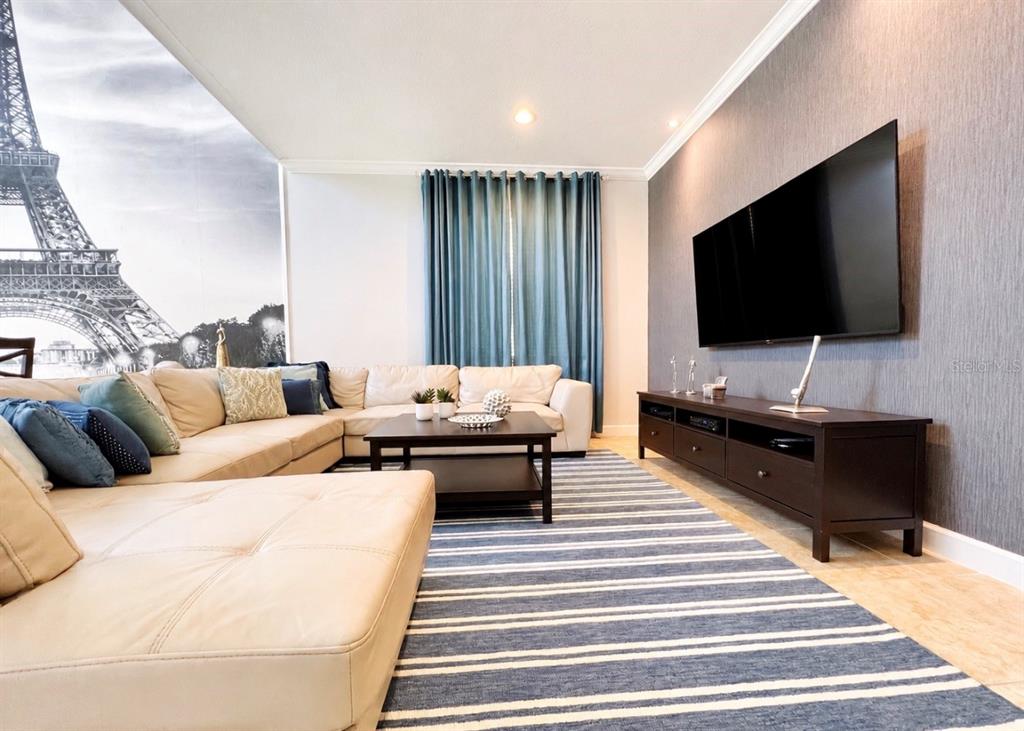A living room features a large sectional sofa, a striped rug, and an Eiffel Tower mural — 8932 BISMARCK PALM ROAD, KISSIMMEE, FL