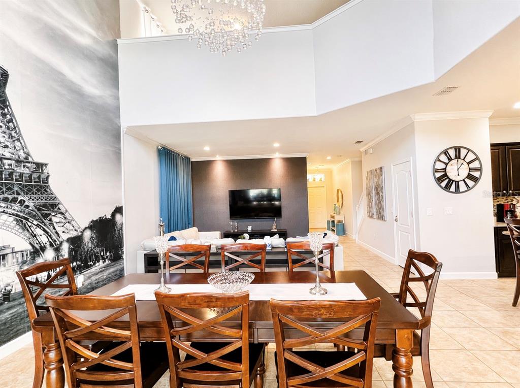 A dining area with a wooden table and chairs sits before a living room — 8932 BISMARCK PALM ROAD, KISSIMMEE, FL