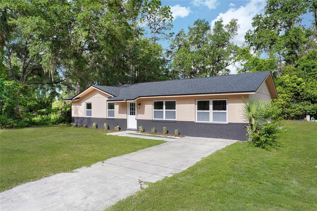 A single-story house with a tan and dark gray exterior sits on a grassy lot — 111 ELM AVENUE, PALATKA, FL