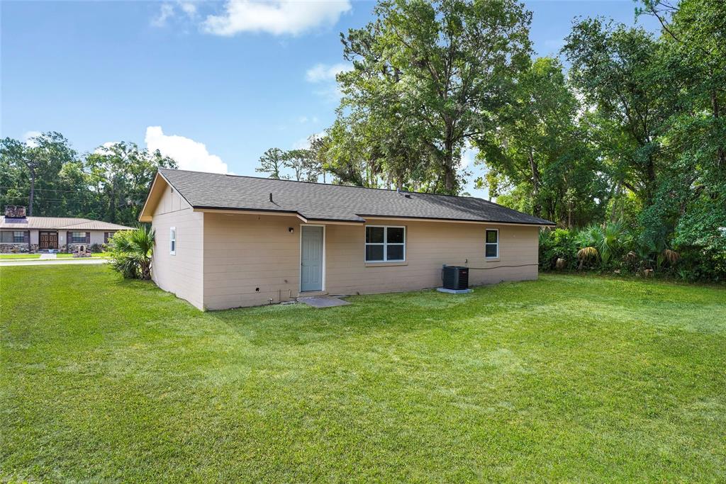 The exterior of a tan, single-story house features a gray door, windows, and an air conditioner — 111 ELM AVENUE, PALATKA, FL