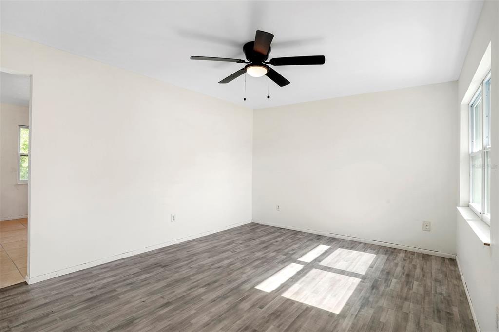 An empty bedroom features light-colored walls, gray wood-look flooring, and a ceiling fan — 111 ELM AVENUE, PALATKA, FL