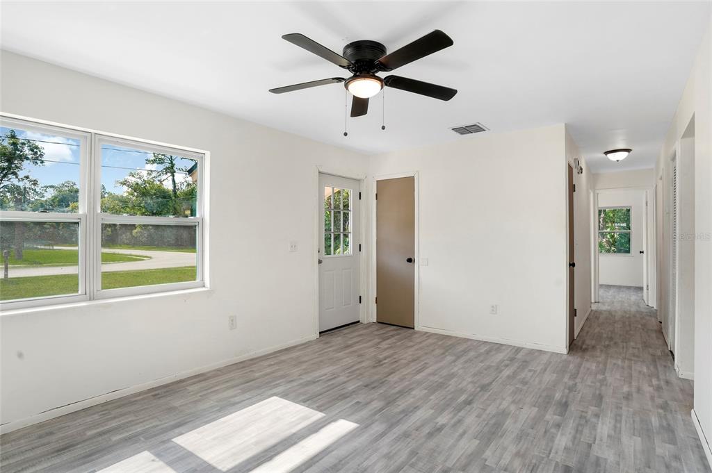 A room with light-colored walls, gray wood-look flooring, a ceiling fan, and a door — 111 ELM AVENUE, PALATKA, FL