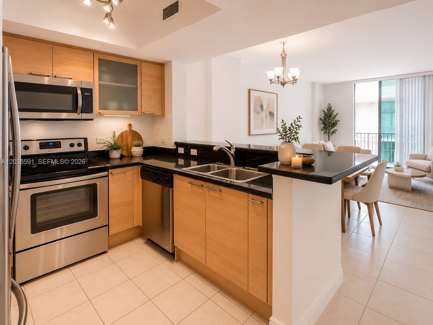 A kitchen with light wood cabinets, stainless steel appliances, and a black countertop peninsula — 140 S Dixie Hwy # 433, Hollywood FL 33020, HOLLYWOOD, FL