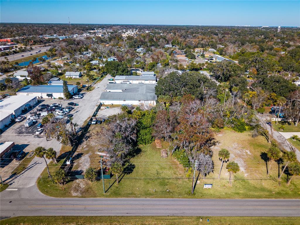 An aerial view shows a vacant grassy lot adjacent to a commercial building and parking area — 818 6TH STREET, DAYTONA BEACH, FL