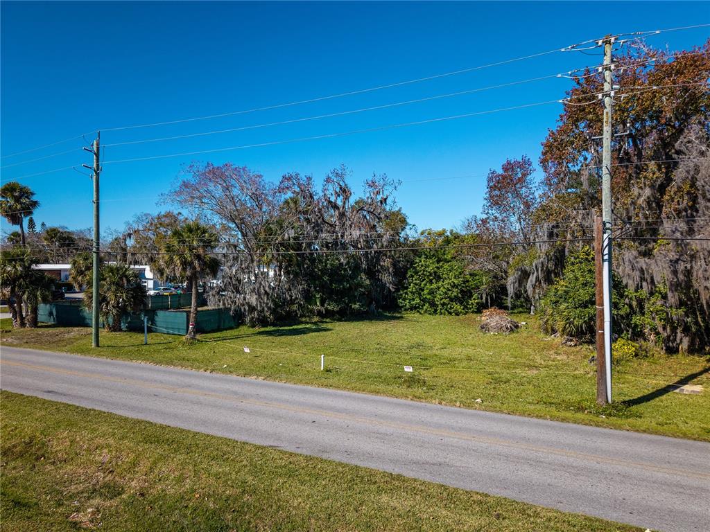 An empty, grassy lot sits alongside a paved road with utility poles and trees — 818 6TH STREET, DAYTONA BEACH, FL