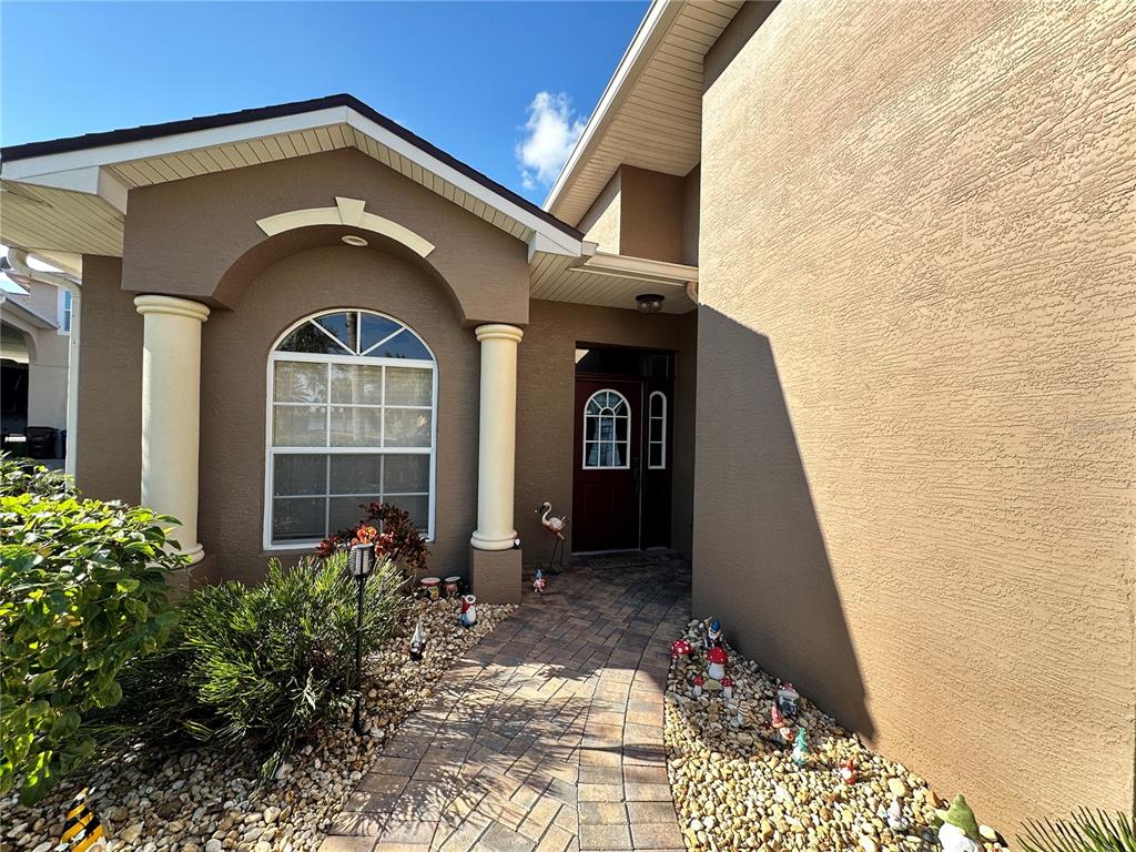 The exterior of a house features a paved walkway leading to a dark front door — 394 NOLANE LANE, POLK CITY, FL