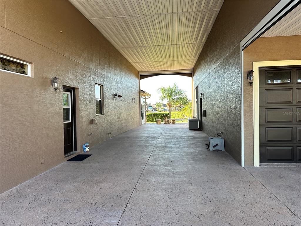 A covered concrete breezeway connects two sections of a house with stucco walls — 394 NOLANE LANE, POLK CITY, FL