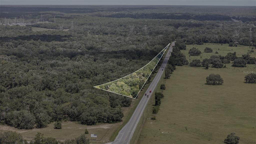 An aerial view shows a triangular wooded lot adjacent to a paved road — 6350 N FLORIDA AVENUE, HERNANDO, FL