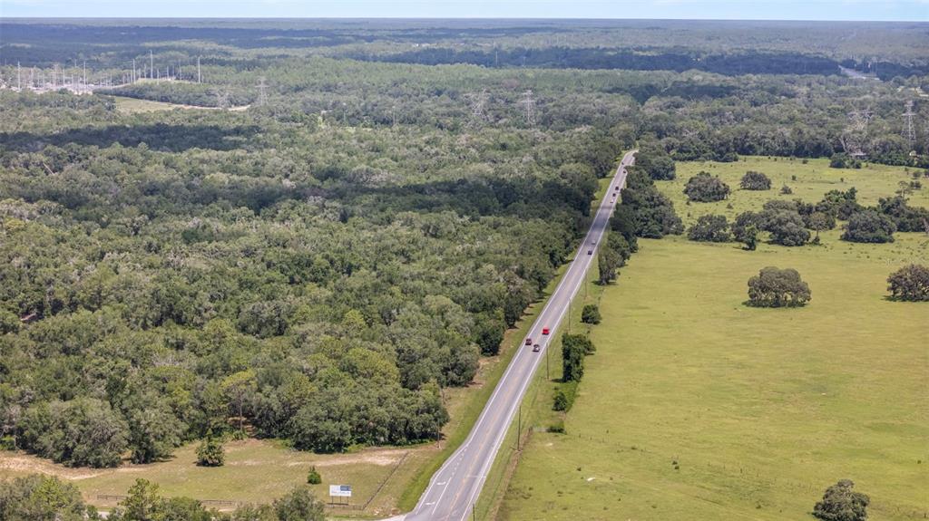 An aerial view shows a rural road dividing a dense forest and an open pasture — 6350 N FLORIDA AVENUE, HERNANDO, FL