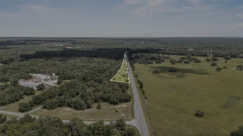 An aerial view shows a triangular wooded lot bordering a paved road and open fields — 6350 N FLORIDA AVENUE, HERNANDO, FL