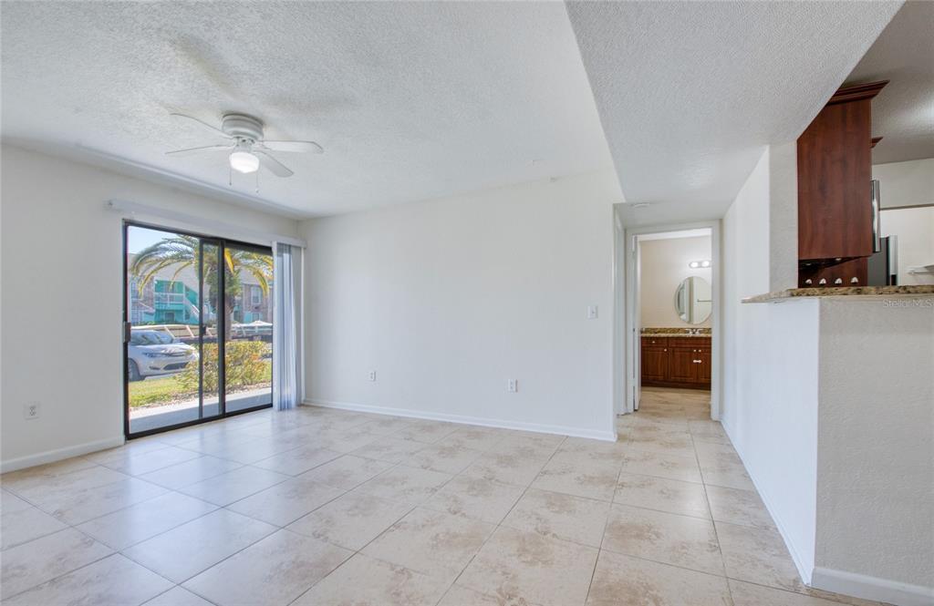 A bright living area features tile flooring, a ceiling fan, and sliding glass doors — 455 ALT 19 S UNIT 21, PALM HARBOR, FL
