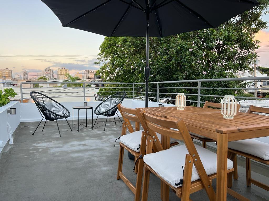 A rooftop terrace features a wooden dining set, two black chairs, and a large umbrella — 50 Ismael Rivera Street OCEAN PARK UNIT 02, SAN JUAN, PR