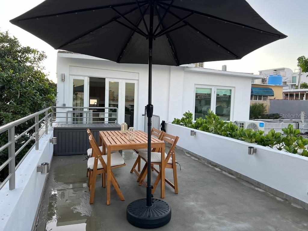 A patio features a wooden dining set with a black umbrella on a concrete rooftop — 50 Ismael Rivera Street OCEAN PARK UNIT 02, SAN JUAN, PR