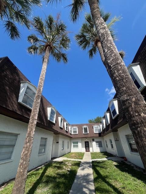 A low-angle view of a two-story apartment building exterior with palm trees and blue sky — 9004 TUDOR DRIVE UNIT K104, TAMPA, FL