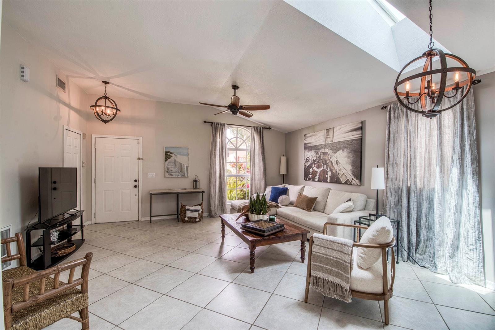 A living room features tile floors, a vaulted ceiling with a skylight, and globe chandeliers — 149 Cypress Cove, Jupiter FL 33458, JUPITER, FL