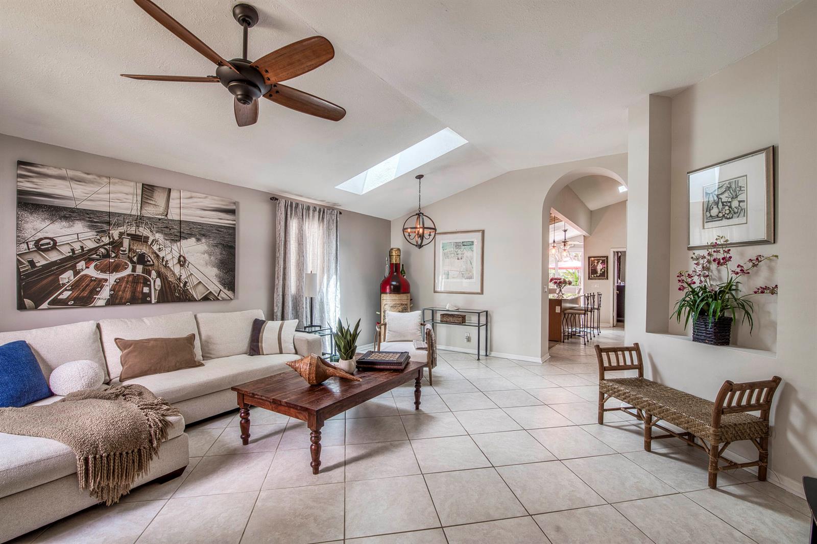 A living room features a vaulted ceiling, skylight, tile flooring, and a large sailboat print — 149 Cypress Cove, Jupiter FL 33458, JUPITER, FL