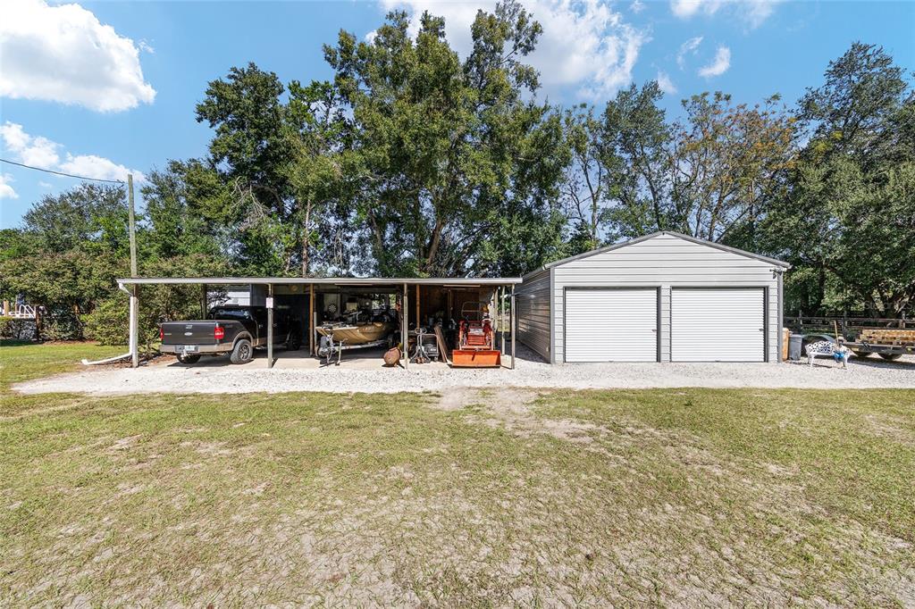 A gravel driveway leads to a metal carport with a boat and a detached garage — 5985 W GULF TO LAKE HIGHWAY, CRYSTAL RIVER, FL