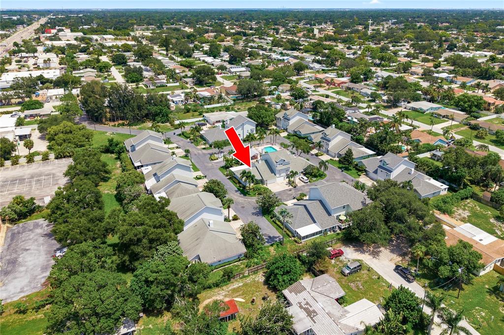 An aerial view shows a residential community with houses, a swimming pool, and surrounding trees — 11722 CURRIE LANE UNIT F1, LARGO, FL