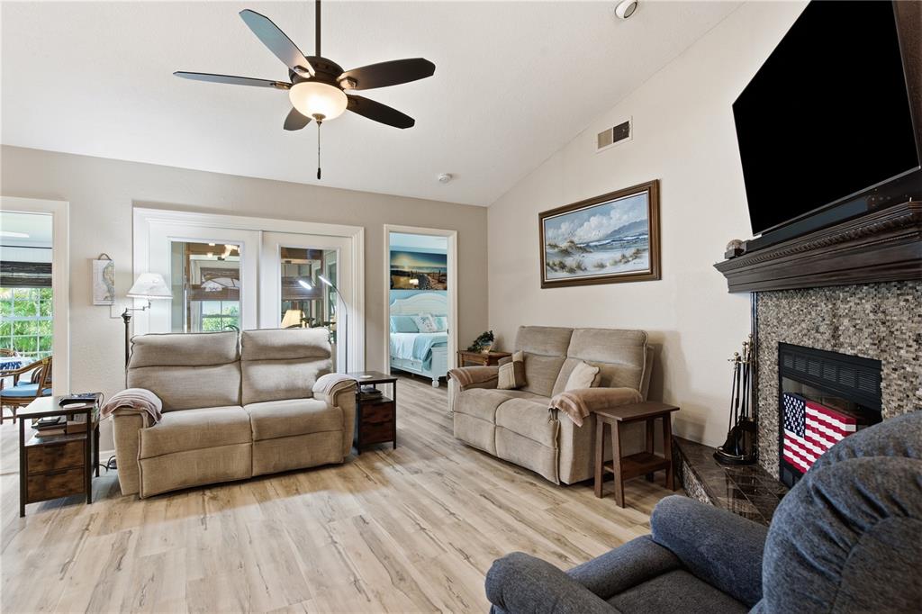 A living room features two beige sofas, a fireplace with a television, and wood flooring — 11722 CURRIE LANE UNIT F1, LARGO, FL