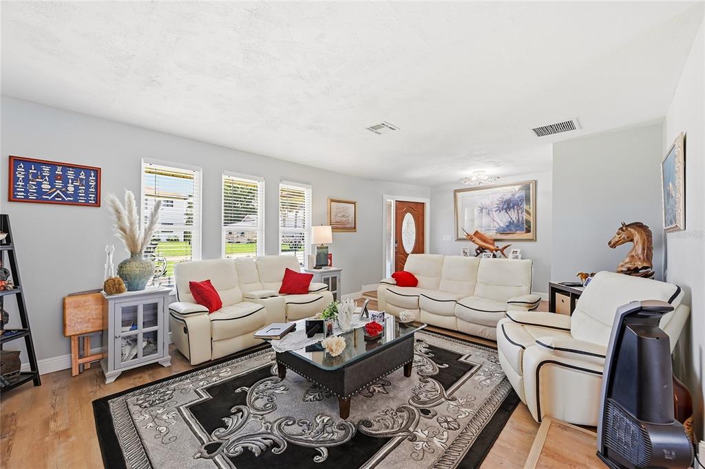 A living room features white leather sofas, a glass-topped coffee table, and a patterned rug — 7219 REYMOOR DRIVE, NORTH FORT MYERS, FL