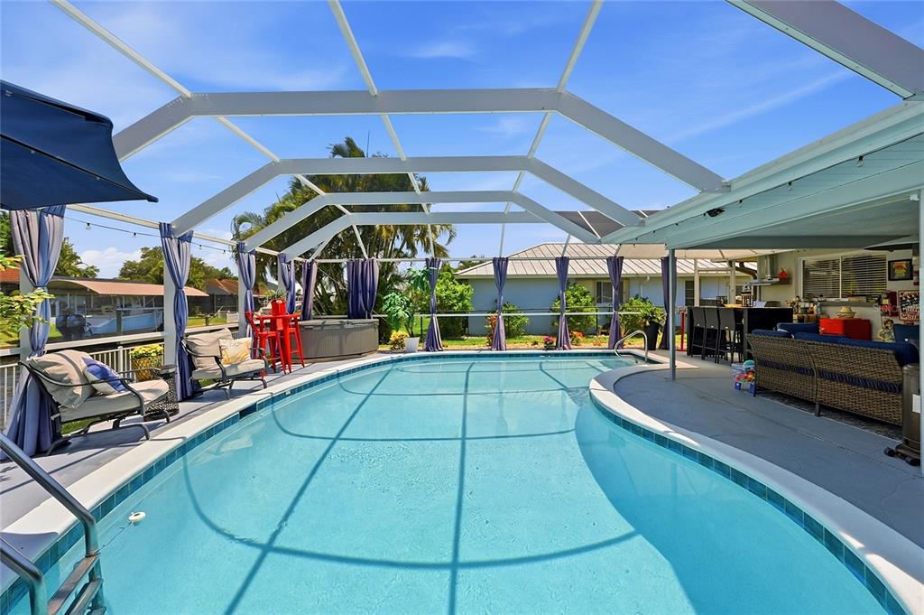 A screened-in swimming pool area with patio furniture and a hot tub under a lanai — 7219 REYMOOR DRIVE, NORTH FORT MYERS, FL