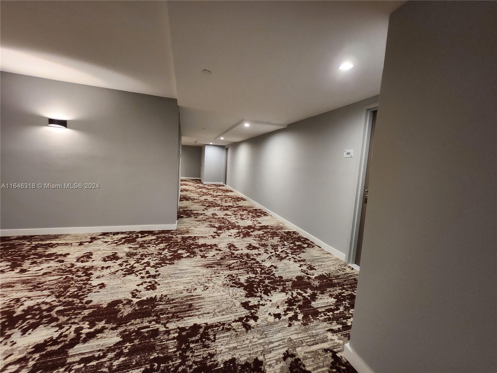 A hallway with gray walls, a patterned brown and white carpet, and recessed ceiling lighting — 2555 Collins Ave # 306, Miami Beach FL 33140, MIAMI BEACH, FL