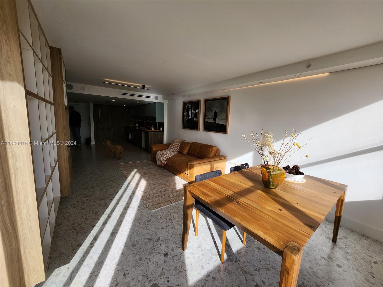 A modern living and dining area features terrazzo flooring, a wooden table, and a leather sofa — 2555 Collins Ave # 306, Miami Beach FL 33140, MIAMI BEACH, FL