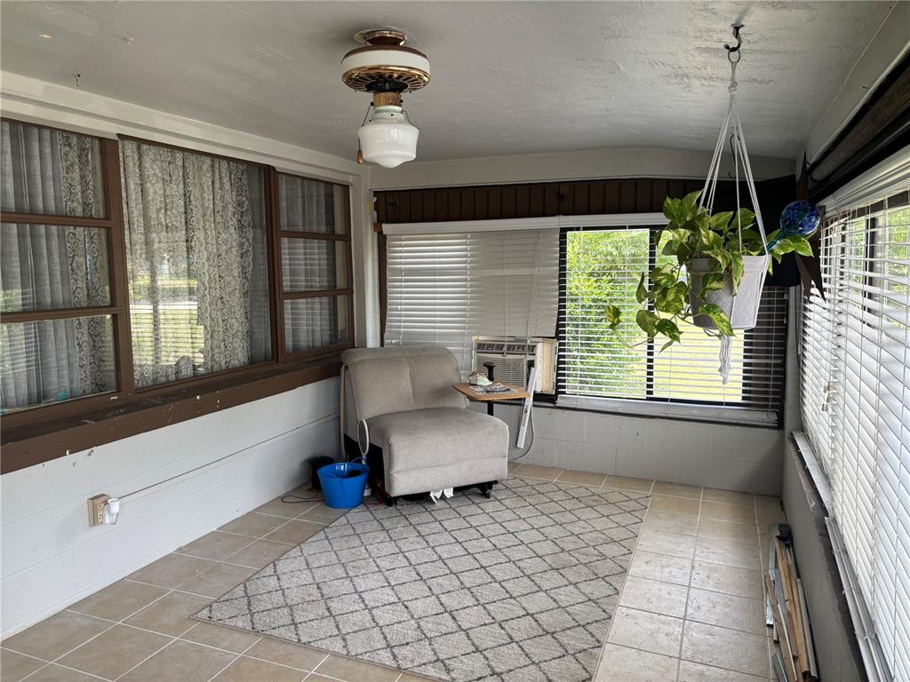 A sunroom with tile flooring, a ceiling fan, a hanging plant, and a single chair — 262 WALTER AVENUE, FROSTPROOF, FL