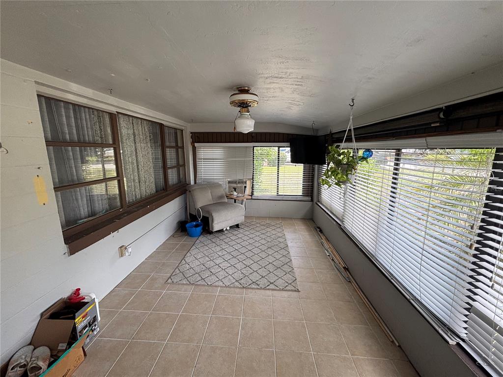 A sunroom features tiled floors, large windows with blinds, a ceiling fan, and a chair — 262 WALTER AVENUE, FROSTPROOF, FL